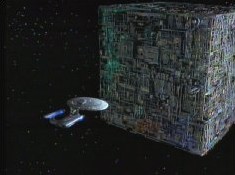 The Federation's flagship, Enterprise, herself an overly large Galaxy Class cruiser, is here seen dwarfed by the truly colossal Borg Cube, during the Borg's first official contact with the Federation, some seven thousand light-years beyond the Federation frontier.